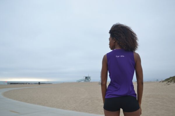 A woman standing on the beach looking out at the ocean.