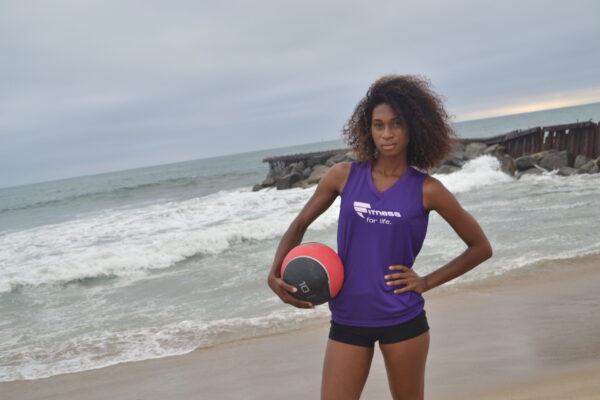 A woman holding a ball on the beach