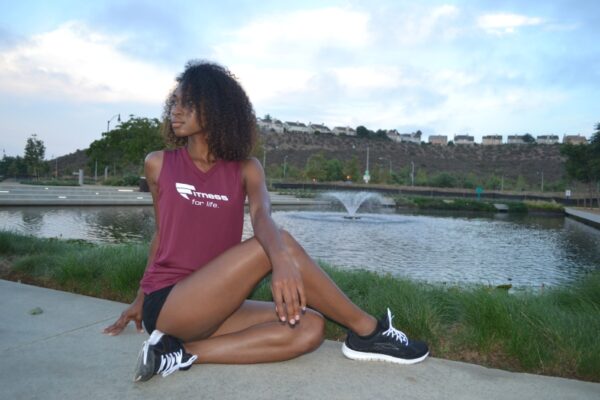 A woman sitting on the ground near a body of water.