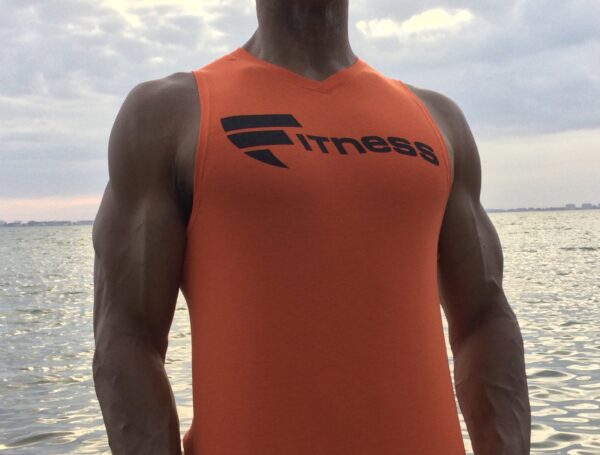 A man in an orange shirt standing on the beach.