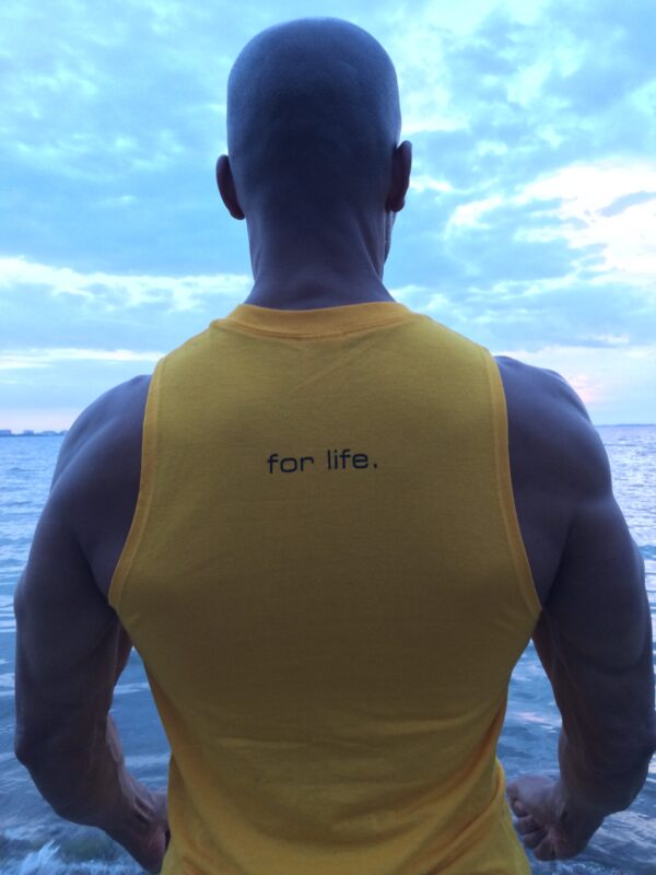 A man in yellow shirt standing on top of a boat.