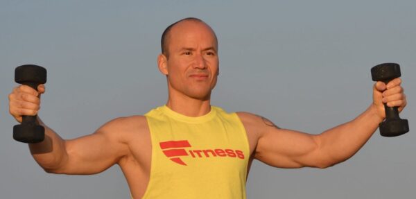 A man in yellow shirt standing on one foot.