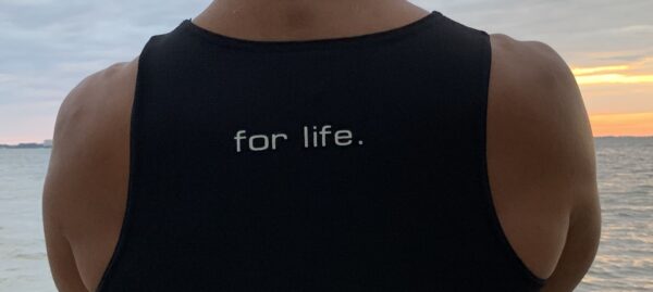 A man wearing a black shirt with the word for life on it.