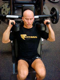 A man is sitting in the gym with two dumbbells.